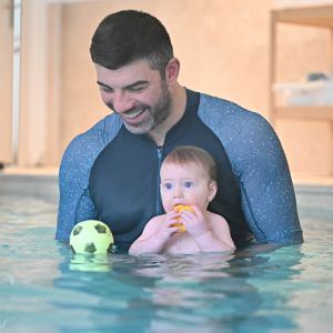 Garçon en bas âge dans les bras du maître nageur