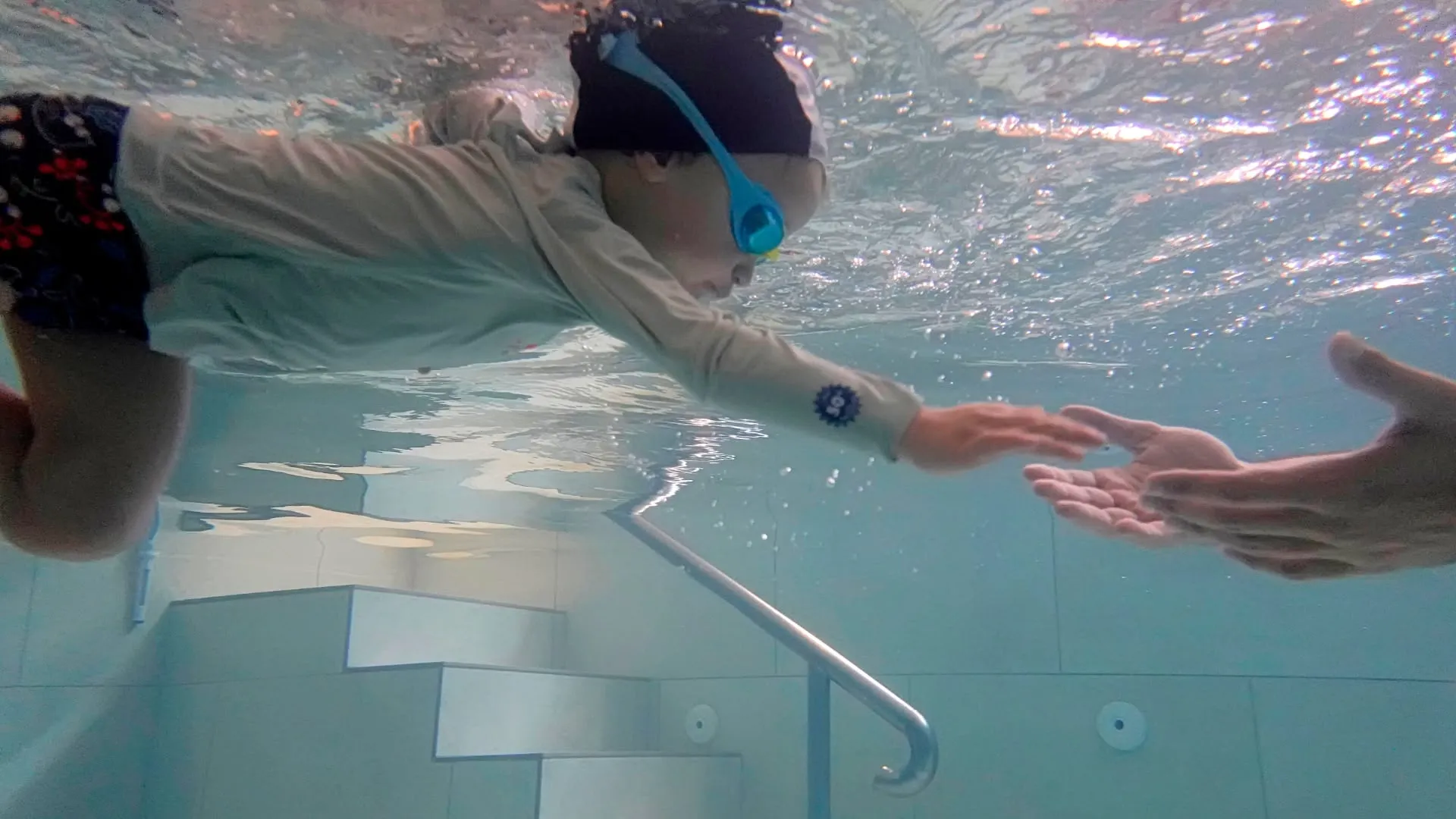 Enfant plongeant sous l'eau rejoignant les bras du maître nageur