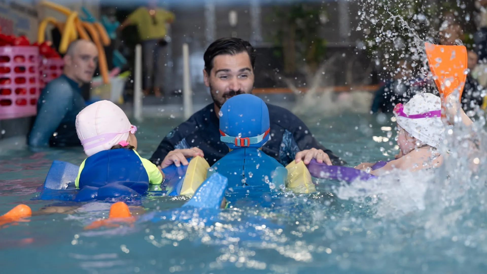 Trois enfants nageant sur une planche vers le maître nageur
