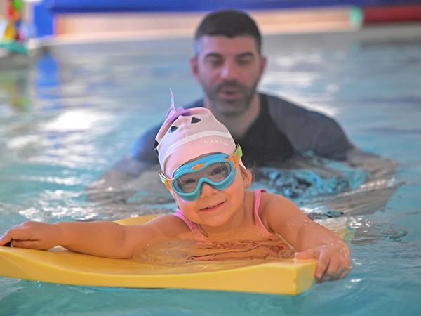 Maître-Baigneur en action apprenant à nager à une petite fille avec du matériel pédagogique