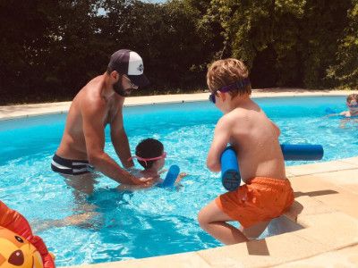 Maître-Baigneur lors d'un cours en petit groupe aidant l'enfant à nager